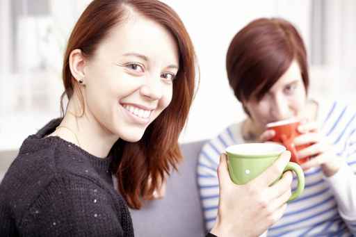 Two happy female friends with coffee cups